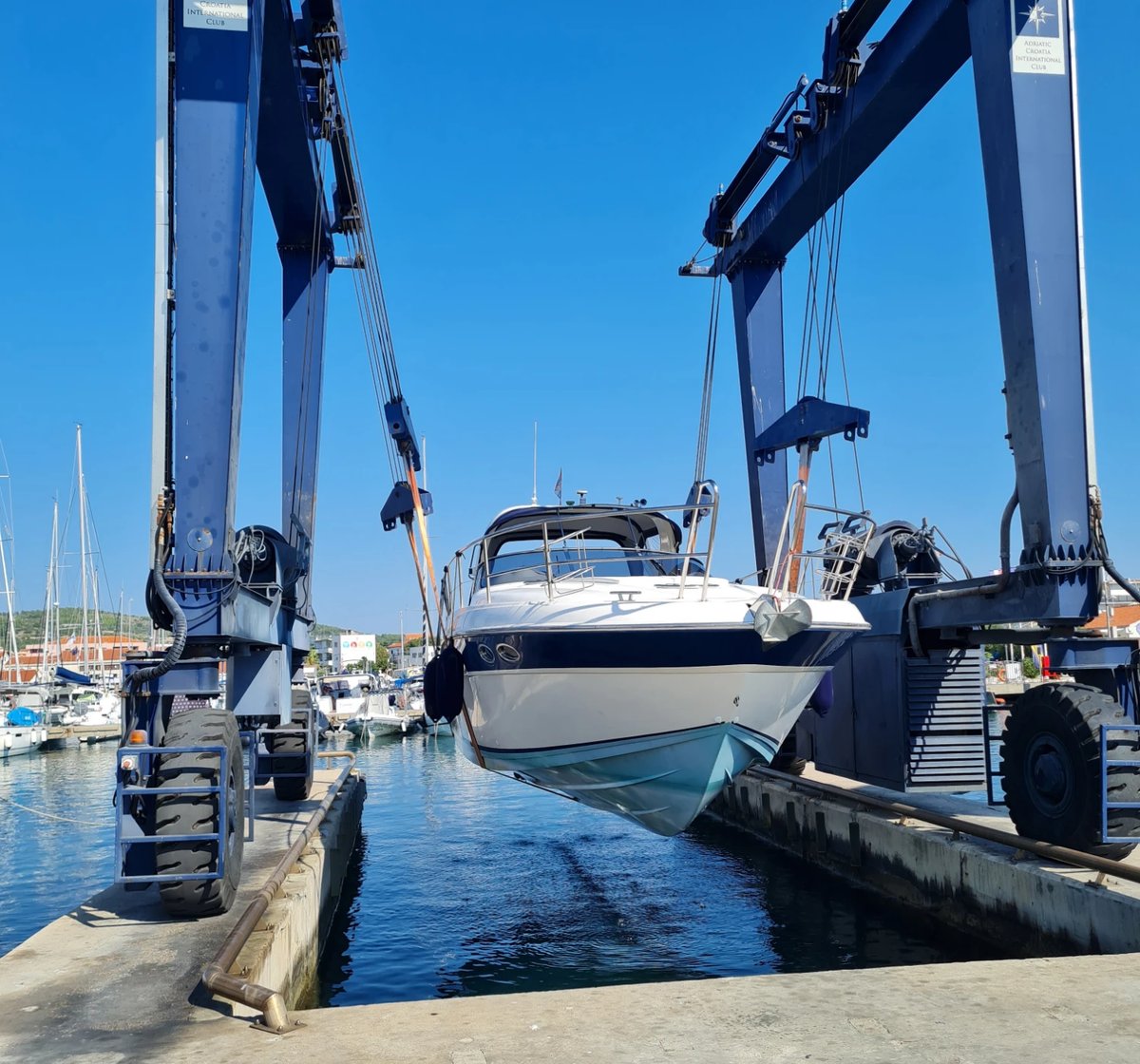 Motorboot hängt im Travellift über dem Hafenbecken