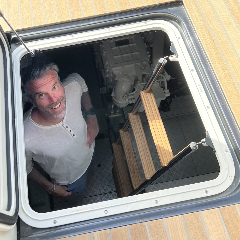Ekki, Gründer von PartABoat, schaut aus der Motorraumluke eines Bootes nach oben