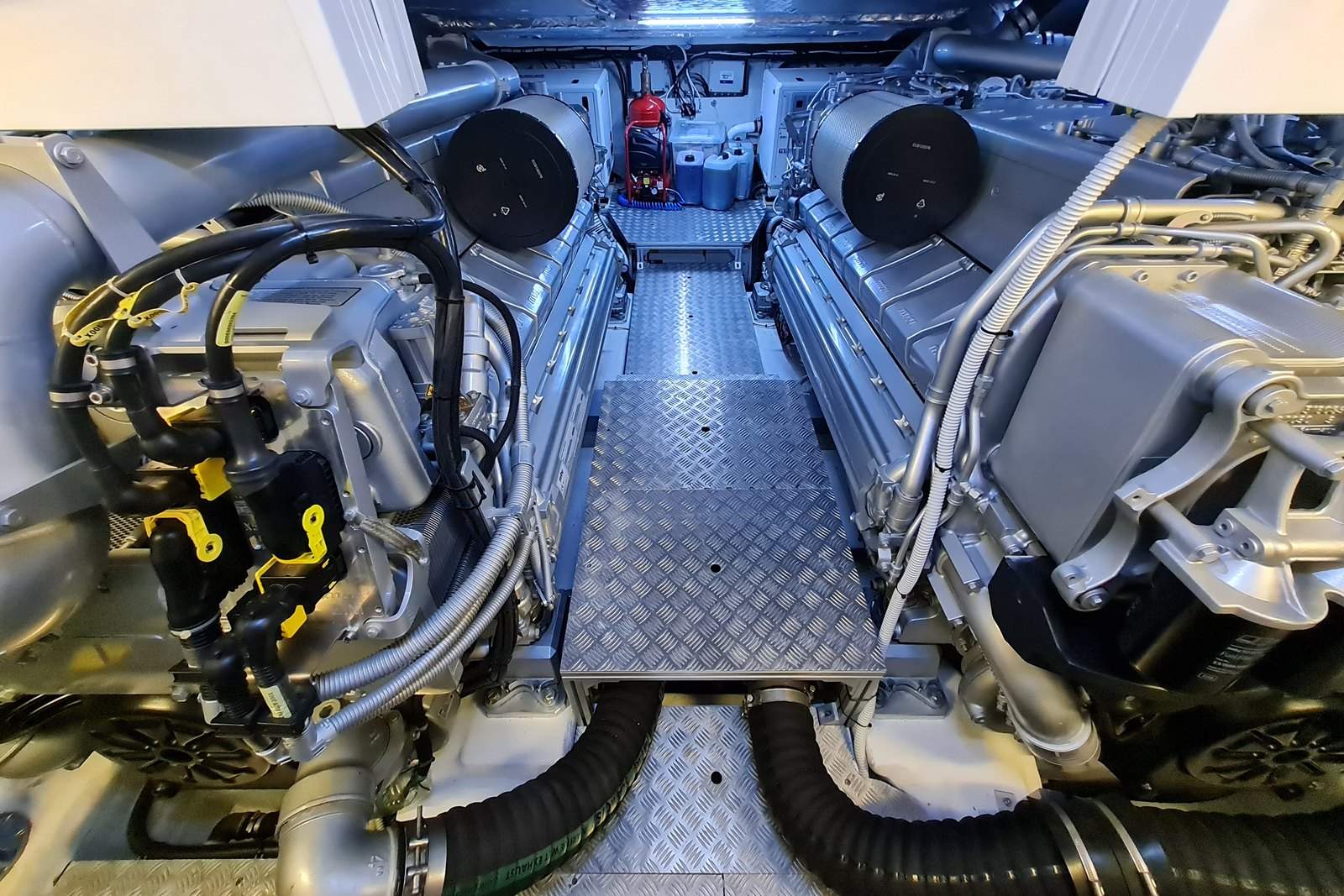 Blick in den Maschinenraum eines Motorboots mit zwei Dieselmotoren und einem Laufrost dazwischen